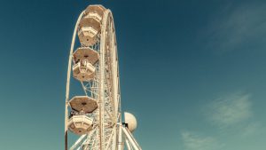 white ferris wheel against a blue sky with a few wisps of white clouds